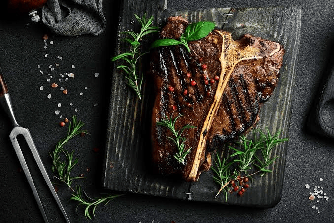Grilled T-Bone steak garnished with fresh herbs at a Greensboro NC steakhouse