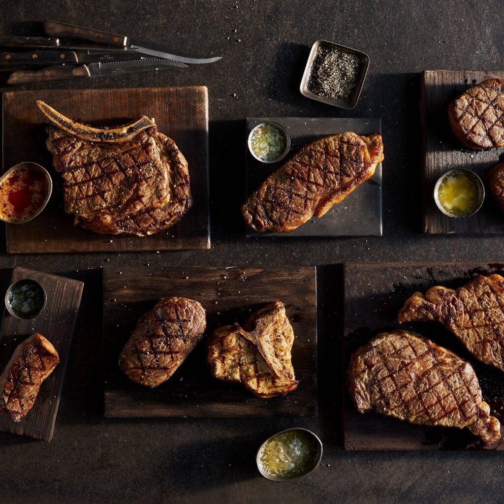 Selection of premium steak cuts displayed on wooden boards at a Greensboro NC steakhouse