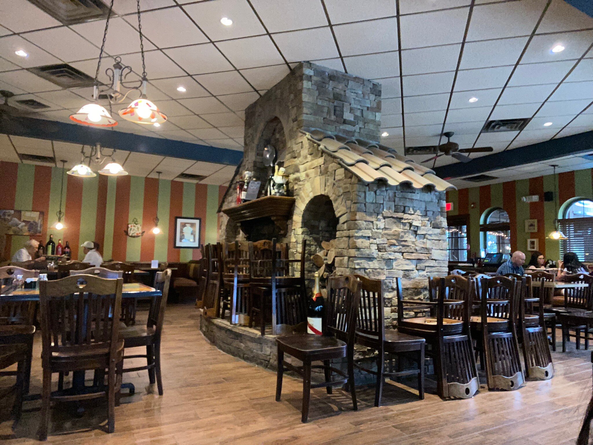 Cozy Italian restaurant interior with rustic stone fireplace and wooden dining tables